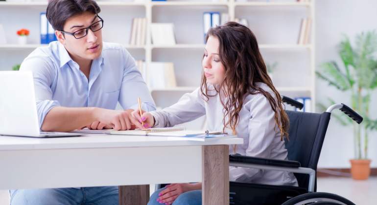 Una chica en silla de ruedas estudia con un tutor