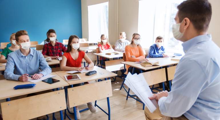 Un profesor da clase en un aula donde todos llevan mascarillas