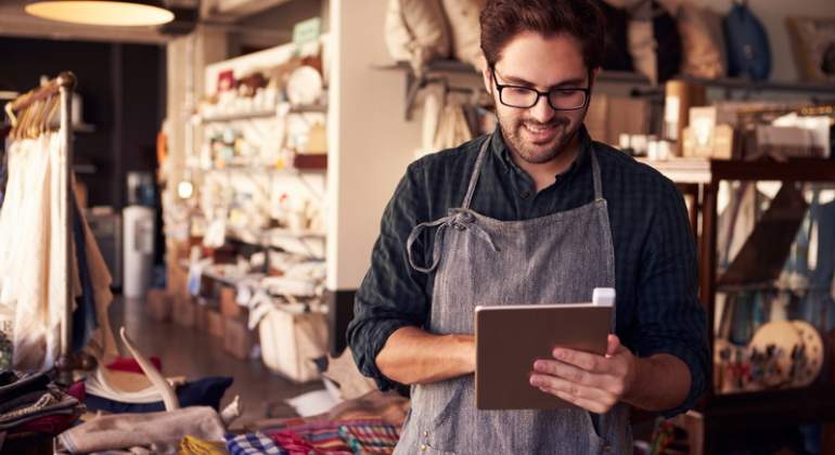 El propietario de una tienda de ropa y regalos usa una tablet