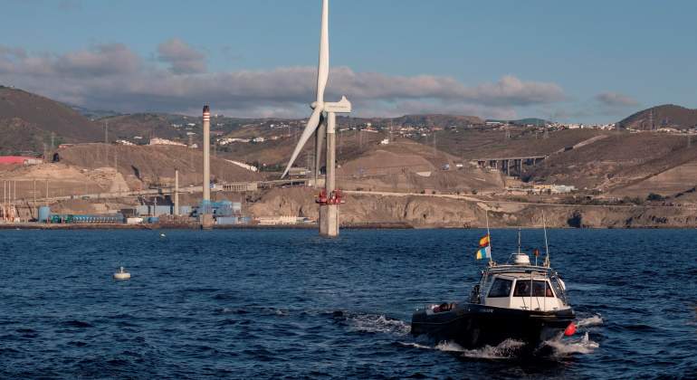 Un aerogenerador en el mar con un barco en primer plano