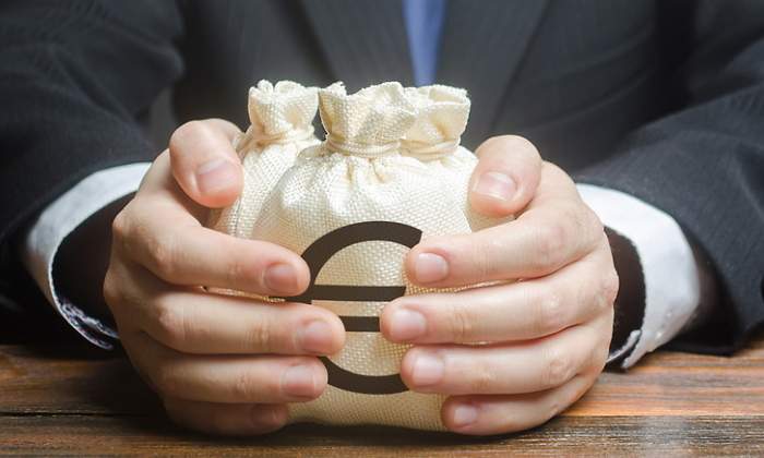 Un hombre con traje coge dos bolsas con el smbolo del euro