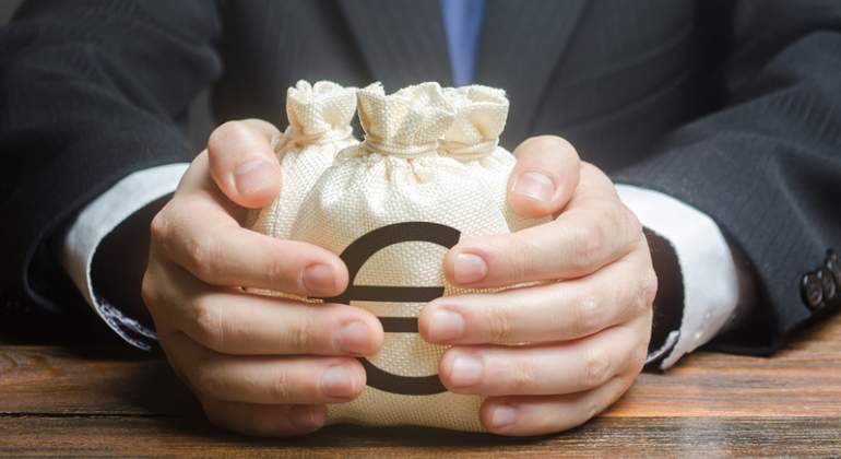 Un hombre con traje coge dos bolsas con el smbolo del euro