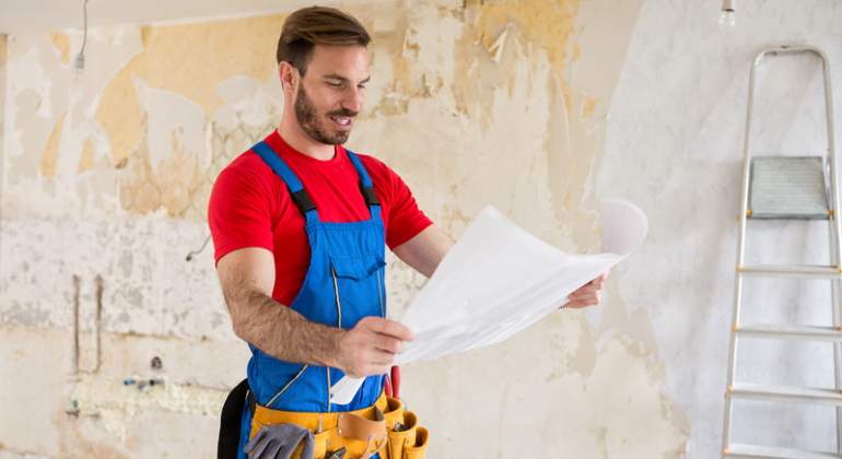 Un hombre mira unos planos para acometer la reforma de una vivienda