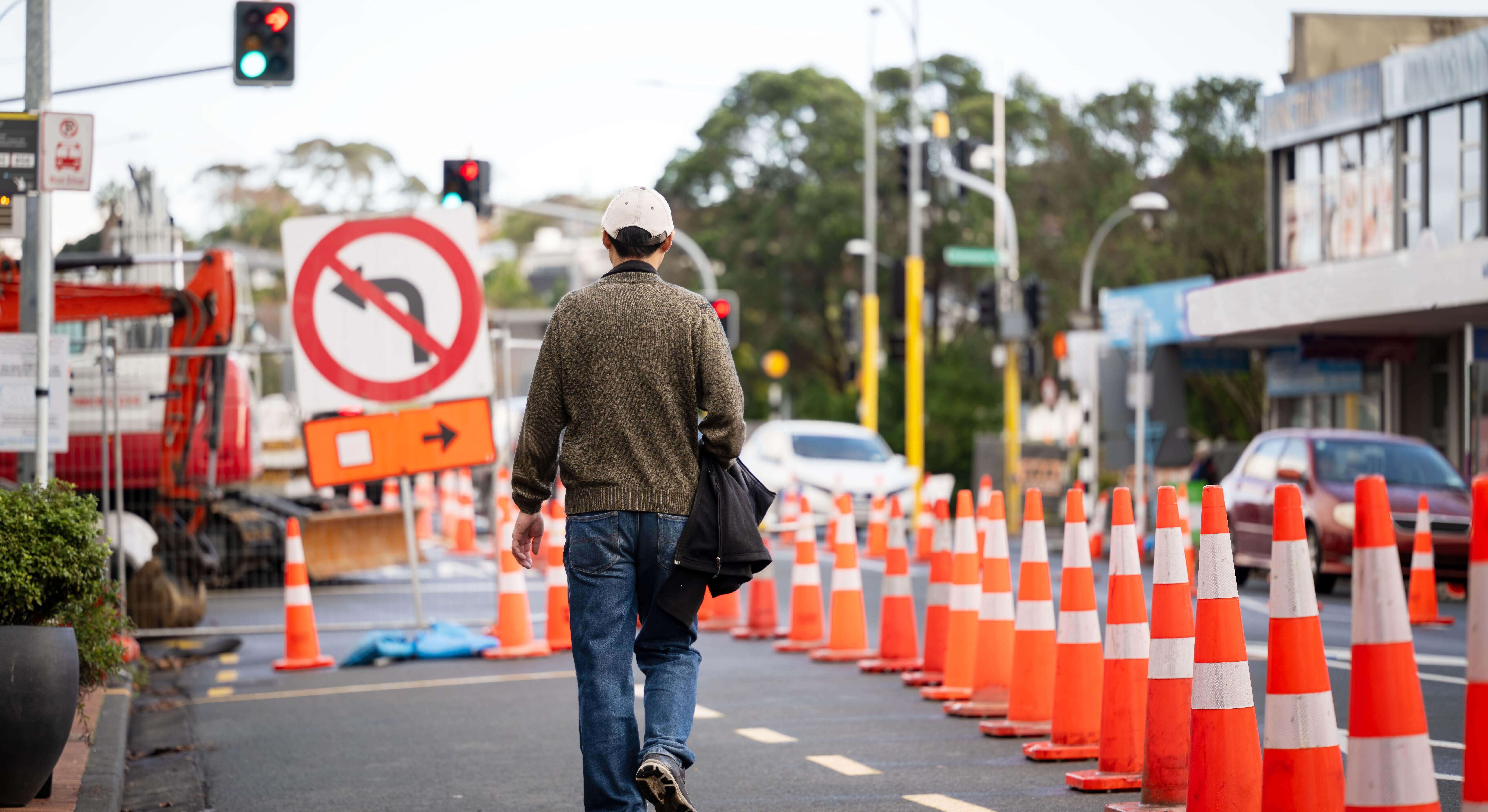 Hombre caminando en paralelo a una fila de conos por obras. Foto: Alamy