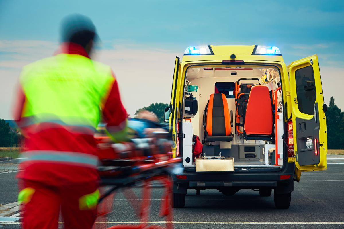 Un profesional del servicio de emergencias traslada a un paciente en camilla hasta una ambulancia | Foto de 123rf/chalabala