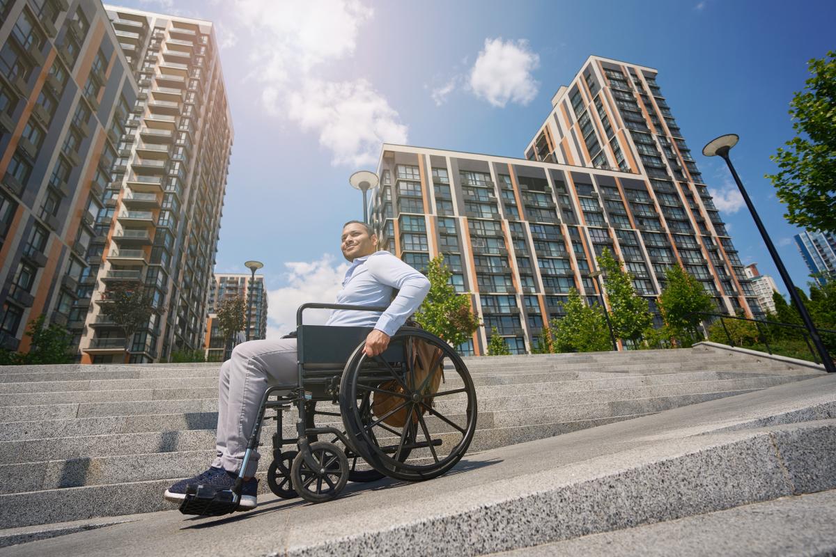 Un hombre en silla de ruedas en medio de la ciudad | Foto de 123rf/yacobchuk