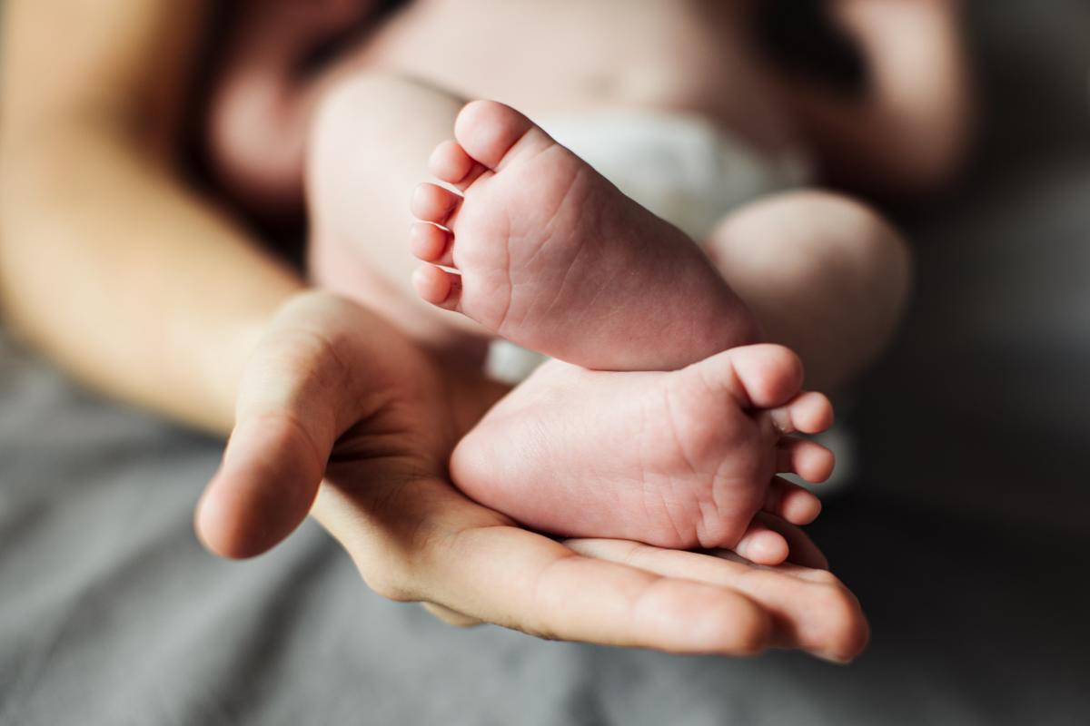 Unas manos sostienen los pies de un recién nacido | Foto de 123rf/adrinn15