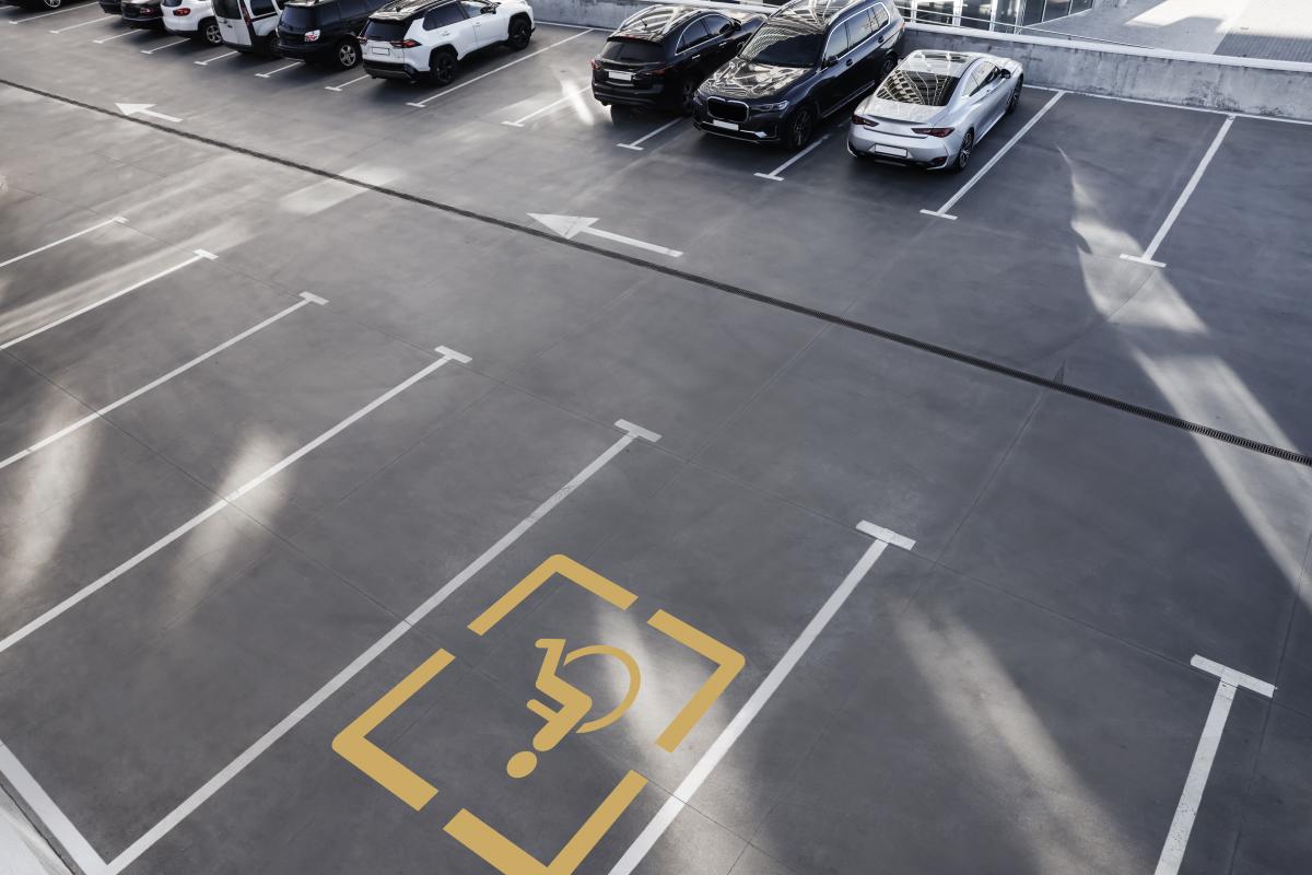Aparcamiento en superficie con una plaza reservada para personas con movilidad reducida | Foto de 123rf/liudmilachernetska