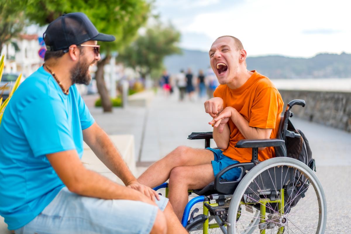 Joven con discapacidad conversando con un amigo | Foto de 123rf/unaihuizi